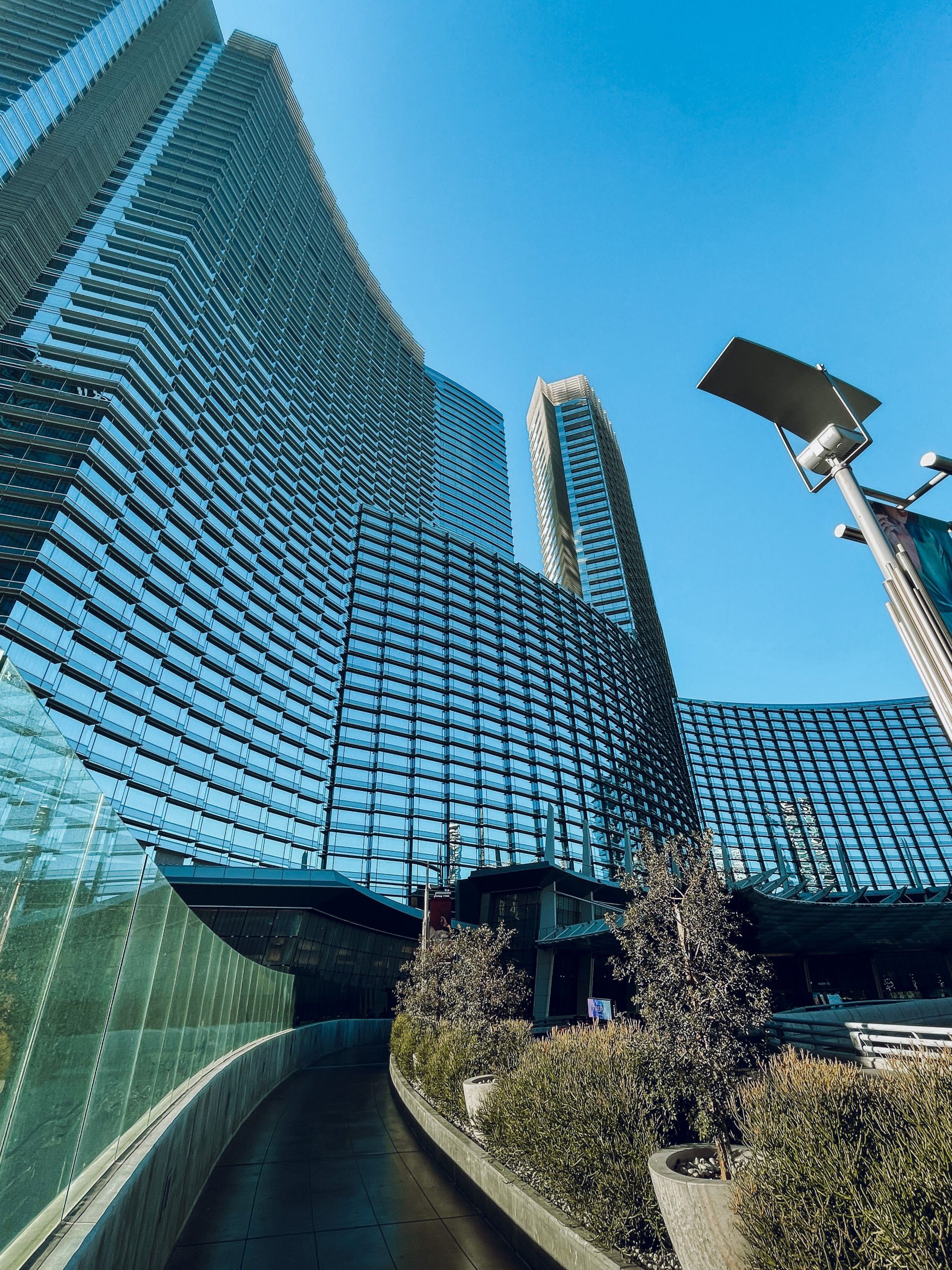 Low angle view of modern skyscrapers with glass facades against a clear blue sky.