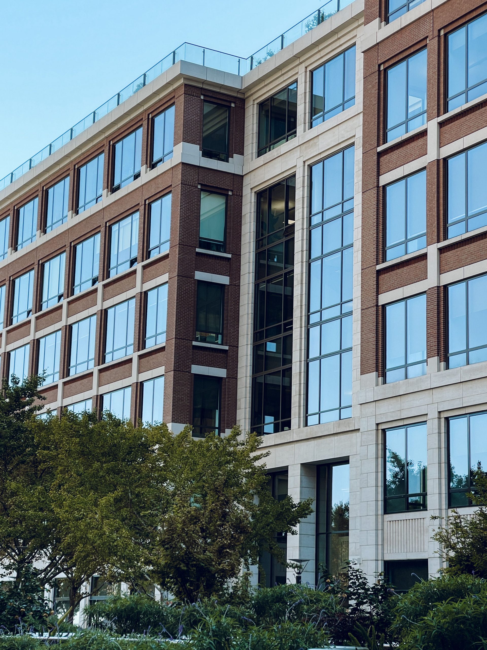 Contemporary office building exterior featuring large glass windows and green surroundings.