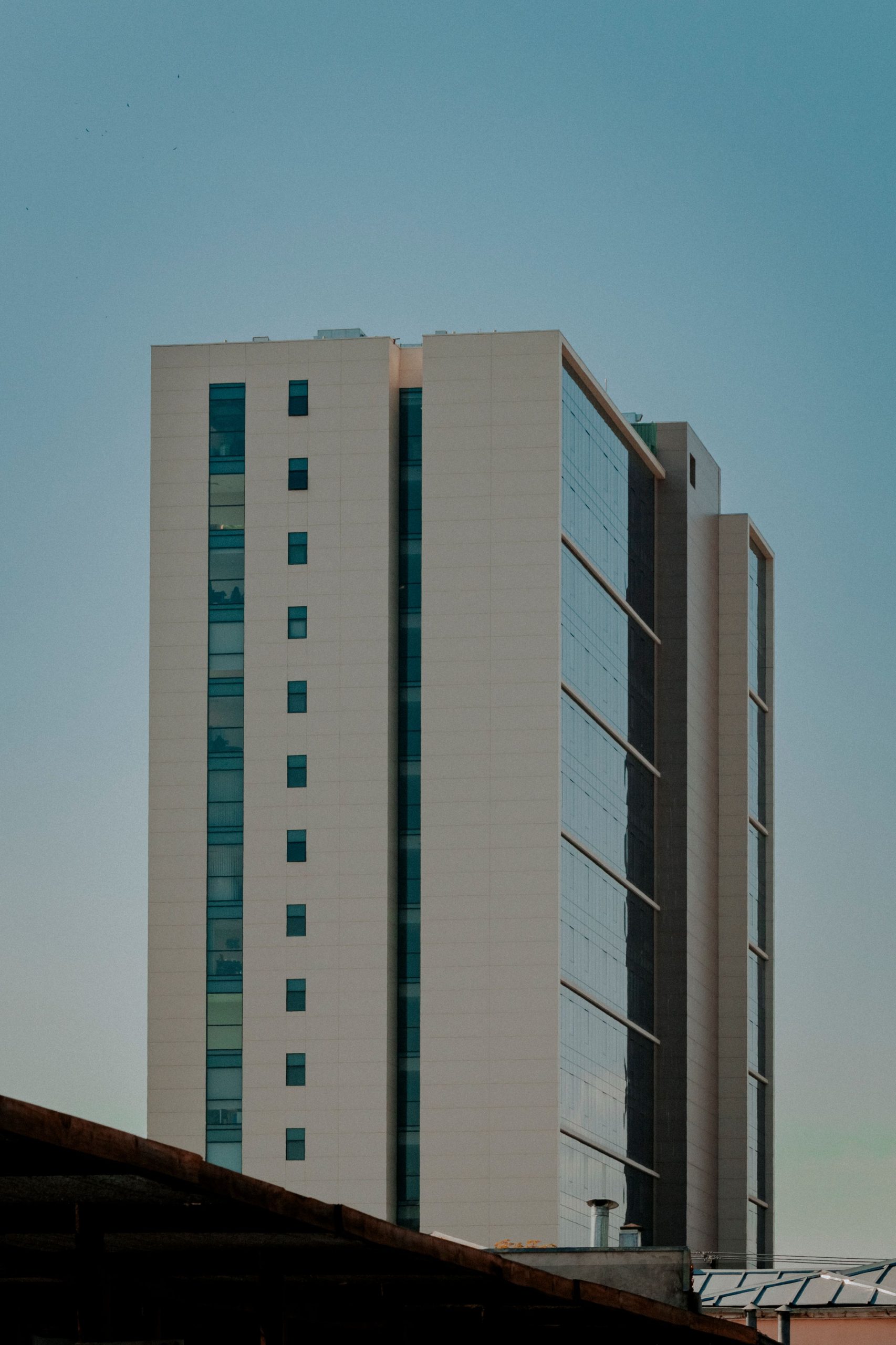 Tall skyscraper in urban setting with minimalist design and clear sky.