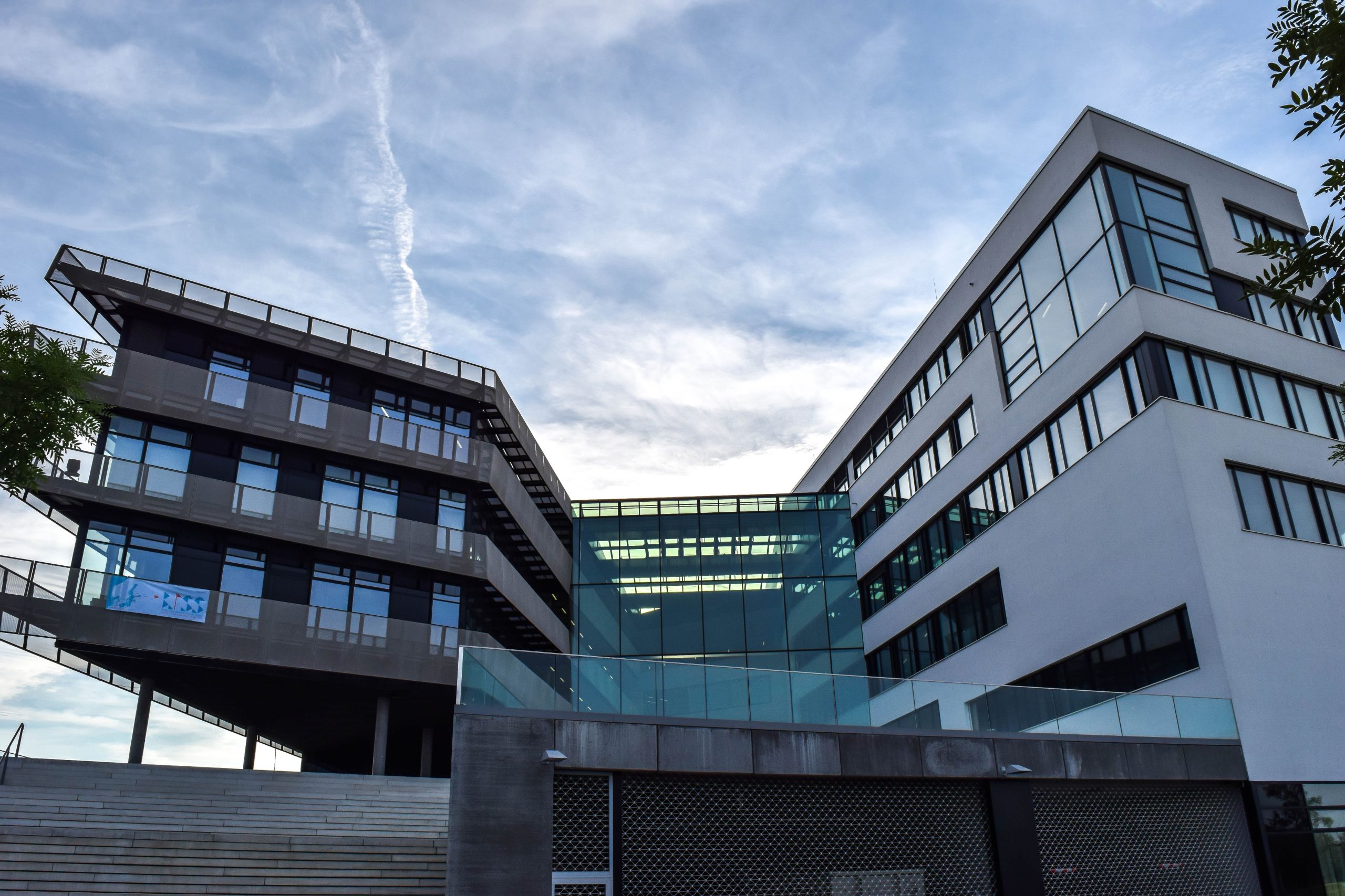 A modern glass-facade building against a blue sky, featuring innovative architecture.